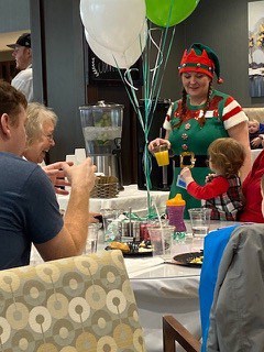a woman dressed as an Elf holding a drink talking to a little girl at a party held by Traditions of Lebanon