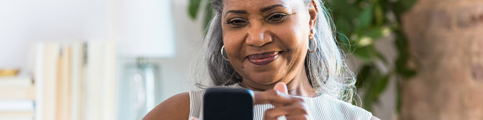 Senior woman with grey hair smiling and looking at phone