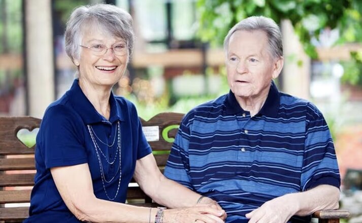 A happy couple sit on a park bench enjoying the outdoors at Traditions of Lebanon in Lebanon, OH.