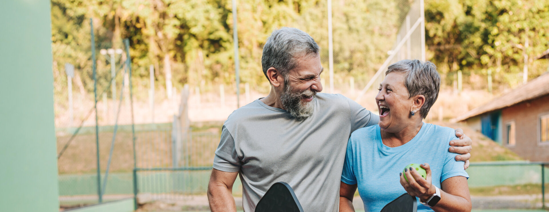 Elderly couple embracing after playing pickle ball.
