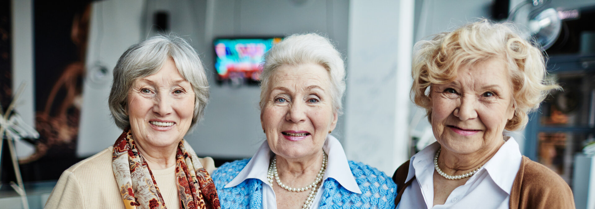 Group of elderly woman with their arms around each other smiling warmly for the camera