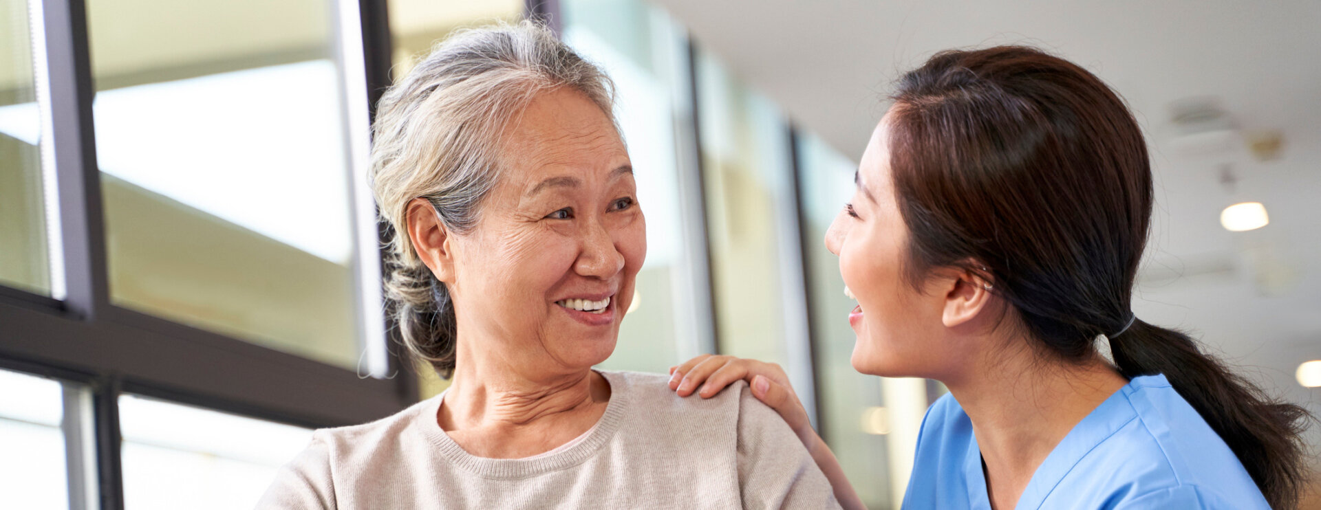 Asian nurse assisting an elderly patient.