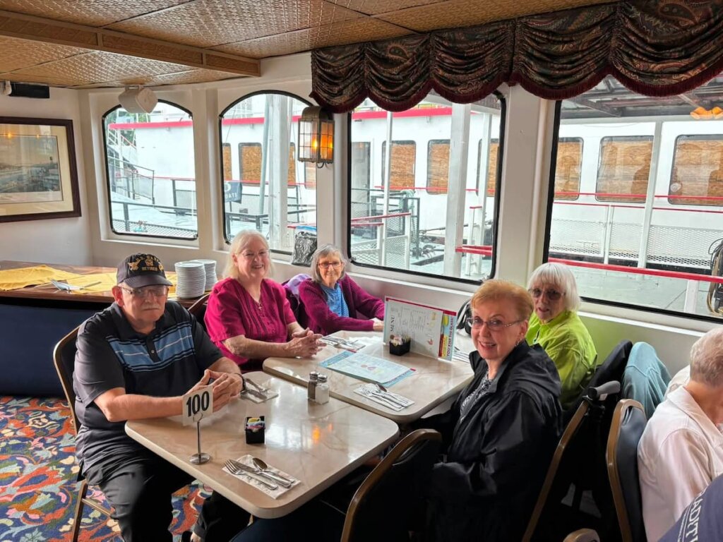 Residents enjoy lunch together during a riverboat cruise as part of a community outing at Traditions of Lebanon